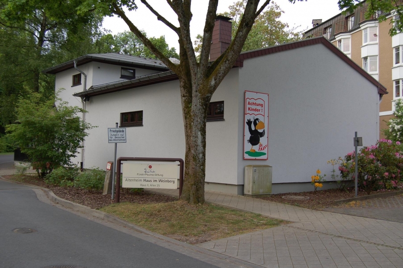  Das Kindergartengebäude von der Straße aus. An der rechten Seite ist ein großes Bild von Rabe Socke zu sehen mit der Aufschrift „Achtung Kinder!“. 