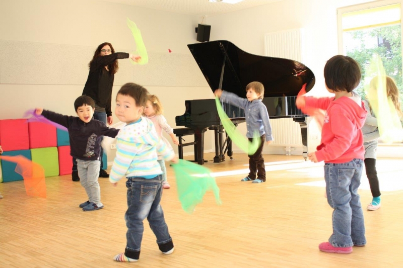 Die musikpädagogische Fachkraft bei der Arbeit mit den Kindern im großen hellen Gemeinschaftsraum mit hauseigenem Flügel  