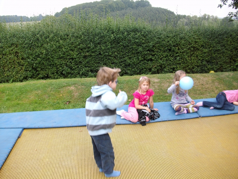 Unser 3x5 Meter großes ebenerdiges Trampolin auf dem Spielplatz bietet allen Kindern zusätzliche Aktivitätsmöglichkeit. Die Umrandung dient zum Ausruhen und Abwarten bis man wieder dran ist.